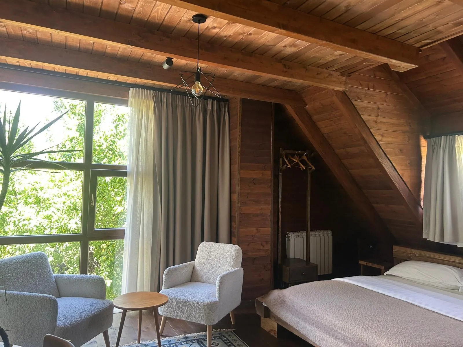 Attic room with timber ceiling, armchairs and a tall window