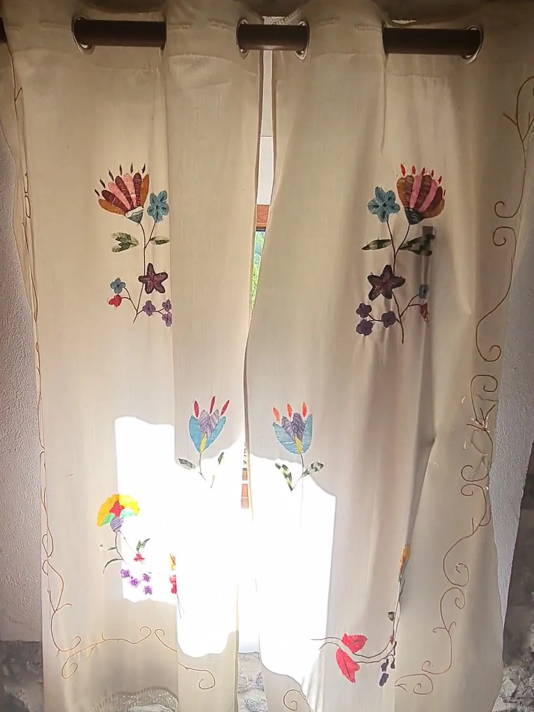 Embroidered curtains against a stone wall