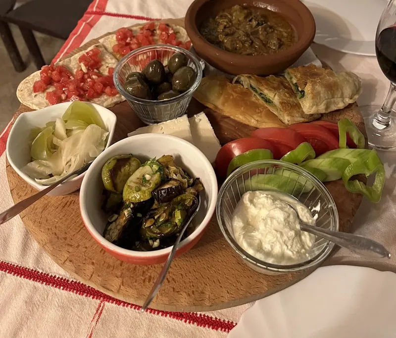 Dinner board with byrek, a clay-pot stew, olives, cheese, roasted vegetables and yogurt