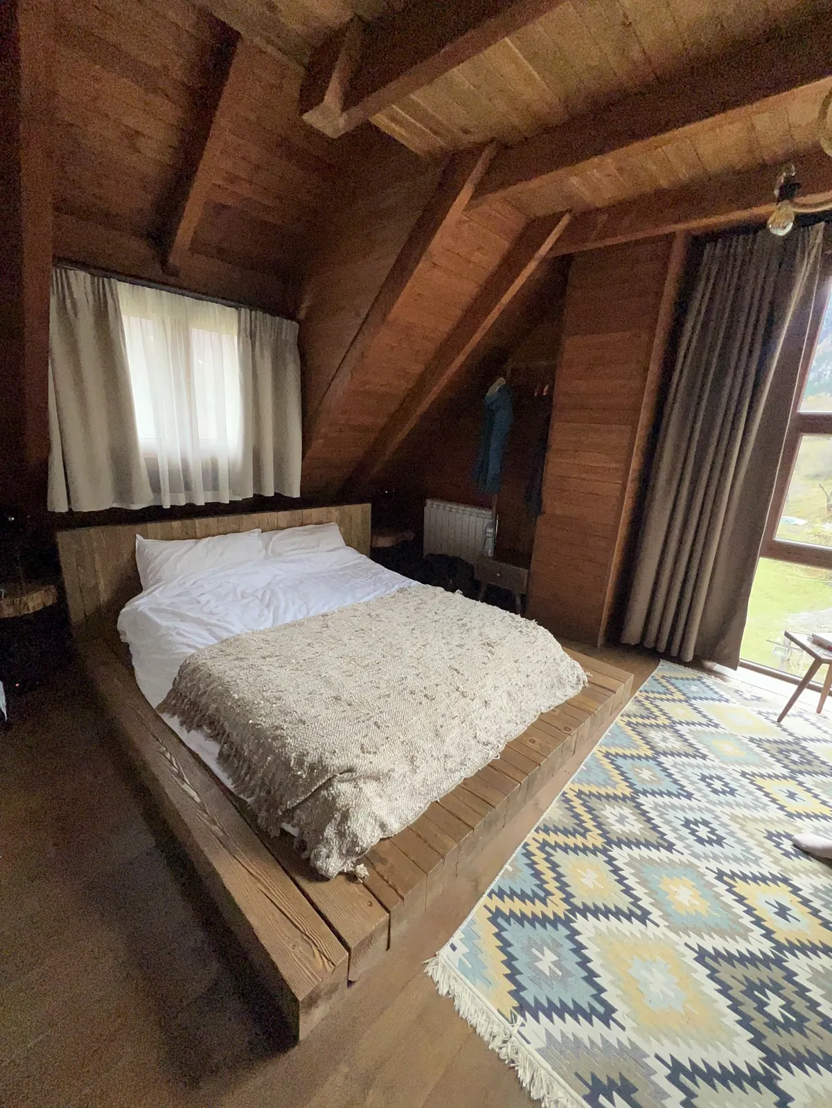 Wooden bed on a timber platform with a kilim