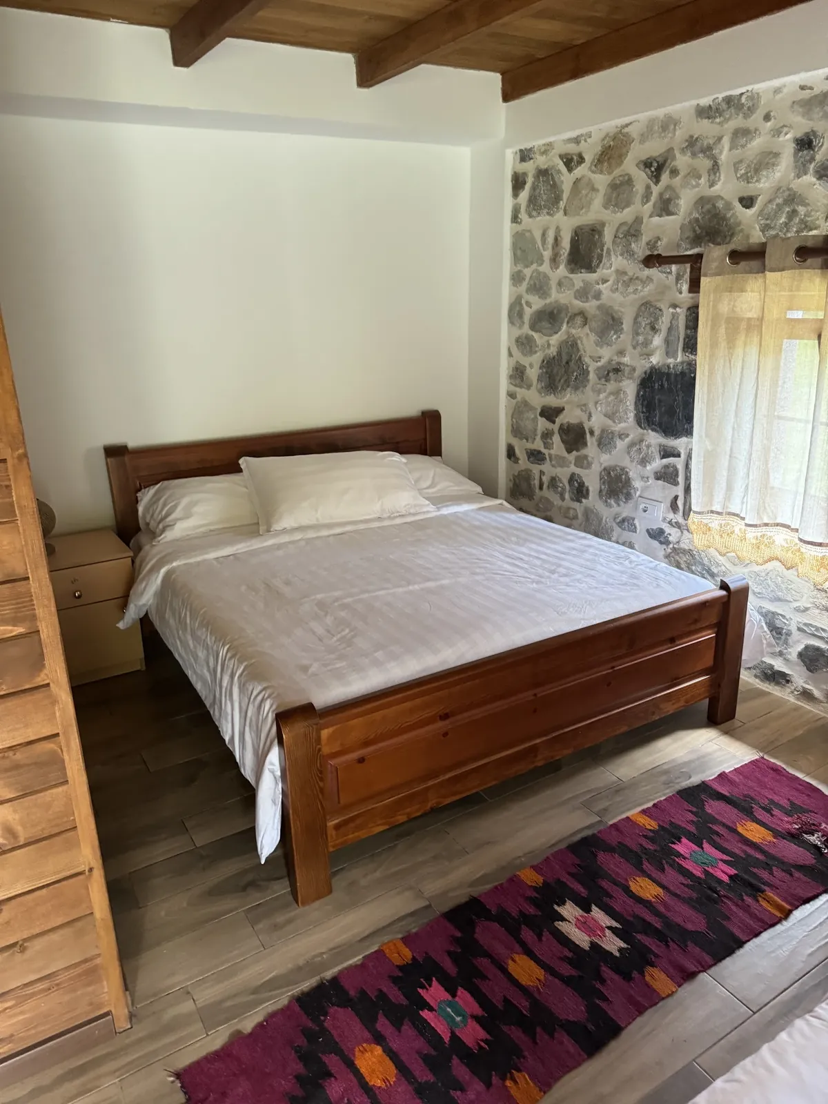 Bedroom with a stone wall and a handwoven rug