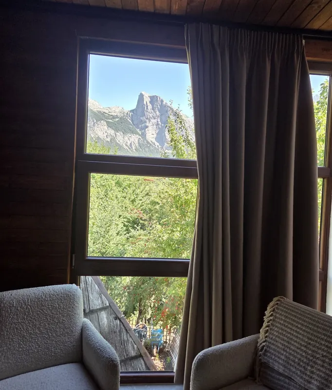 Two armchairs facing a window that frames a sharp limestone peak
